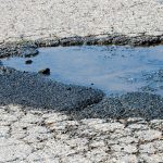 Photo of puddle of water on cracked ground