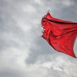 Photo of ripped flag on pole blowing in wind
