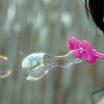 Photo of child blowing bubbles through wand