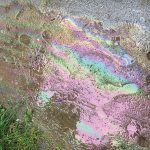 Photo of polluted water with rainbow reflection