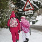Photo of two children walking to school in snow