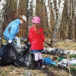 Photo of adult and child cleaning up rubbish in forest
