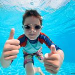 Photo of child giving thumbs-up under water